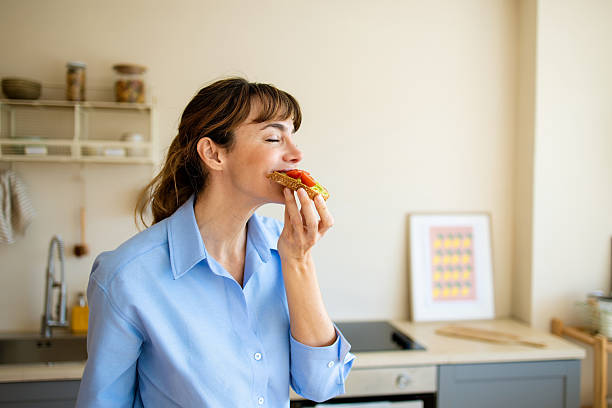 Woman enjoying healthy avocado toast breakfast in kitchen