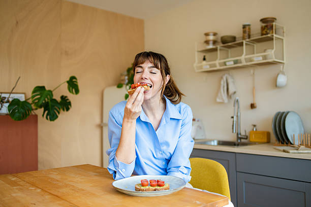 Young woman enjoying healthy bruschetta breakfast in kitchen