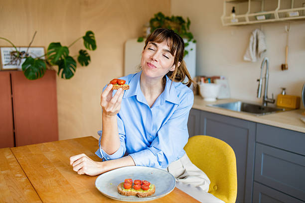 Woman enjoying healthy avocado toast breakfast in kitchen