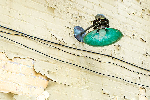 Retro street lamp on the side of a brick building with a pealing painted surface