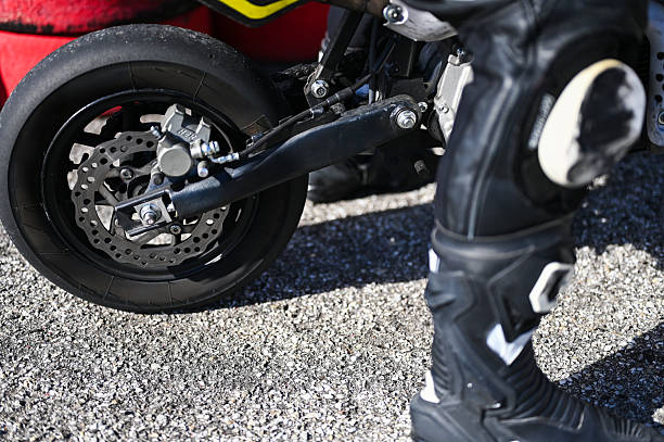 Rider wearing protective gear standing next to a racing motorcycle in the pit lane