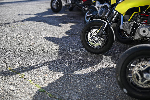 Motorcycles parked outdoors on asphalt, creating long shadows in bright sunshine