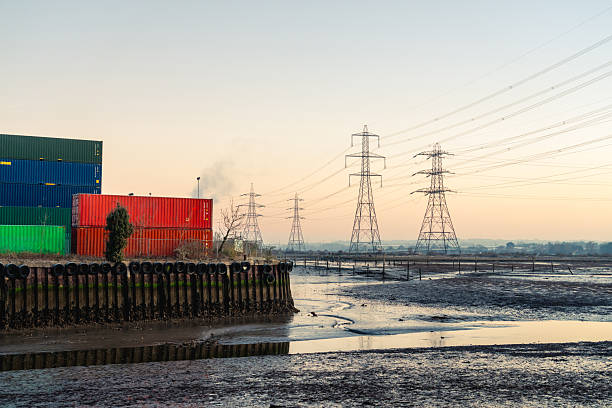 Shipping containers and power lines standing on industrial mudflats in southampton, uk