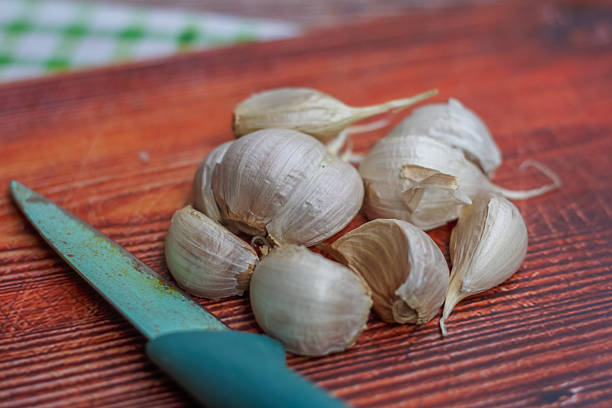 Garlic Cloves and Kitchen Knife on Wooden Cutting Board