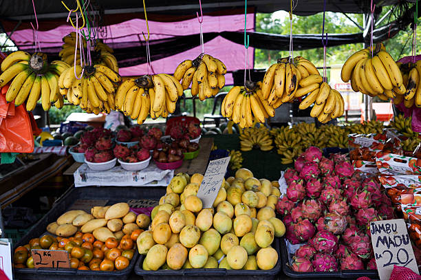 Tropical fruit market stall displaying bananas, dragon fruit, mangoes, oranges