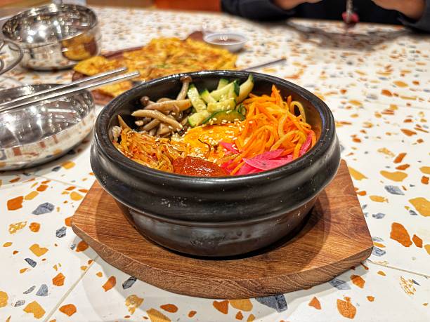 Authentic Dolsot Bibimbap served in a hot stone bowl, featuring fresh vegetables, mushrooms, and savory gochujang sauce