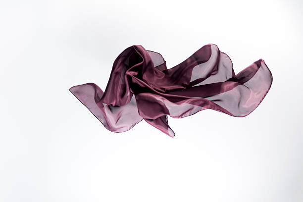 A graceful, flowing piece of translucent purple silk captured in mid-air against a minimalist white backdrop.