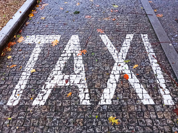 White taxi sign painted on the ground, cobblestone flooring.Galicia, Spain. Taxi only parking space. Autumn leaves.