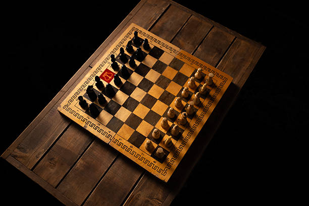 Chessboard on a wooden table with dramatic lighting highlighting a red marked piece