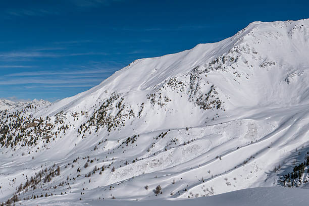 Multiple small slab avalanches visible on a steep snow-covered alpine mountain slope in the Italian Alps. Clear crown lines and avalanche debris areas highlight natural winter mountain hazards and unstable snow conditions in high altitude terrain.