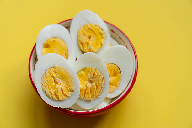 Boiled eggs in a bowl on yellow background