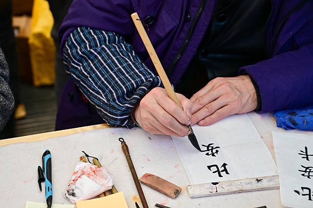 An old Chinese calligrapher is writing calligraphy characters, creating calligraphy names with chinese brush