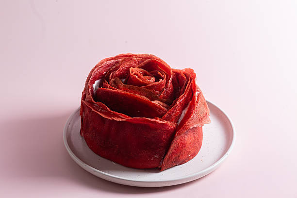 Red velvet pancake cake shaped like a large rose with cream cheese filling, served with cottage cheese and milk. Traditional Maslenitsa or Valentine's Day dessert.