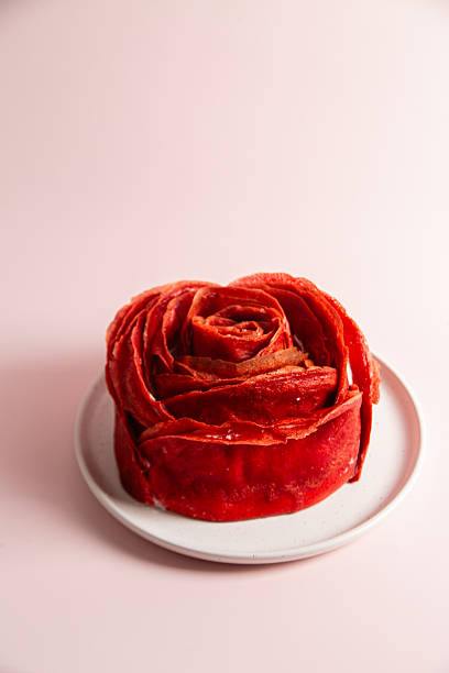 Red velvet pancake cake shaped like a large rose with cream cheese filling, served with cottage cheese and milk. Traditional Maslenitsa or Valentine's Day dessert.