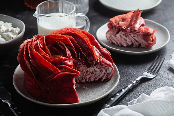 Red velvet pancake cake shaped like a large rose with cream cheese filling, served with cottage cheese and milk. Traditional Maslenitsa or Valentine's Day dessert.