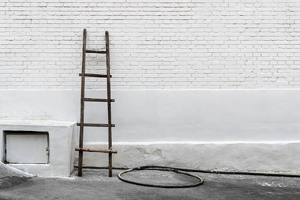 Wooden ladder leaning against a white brick wall