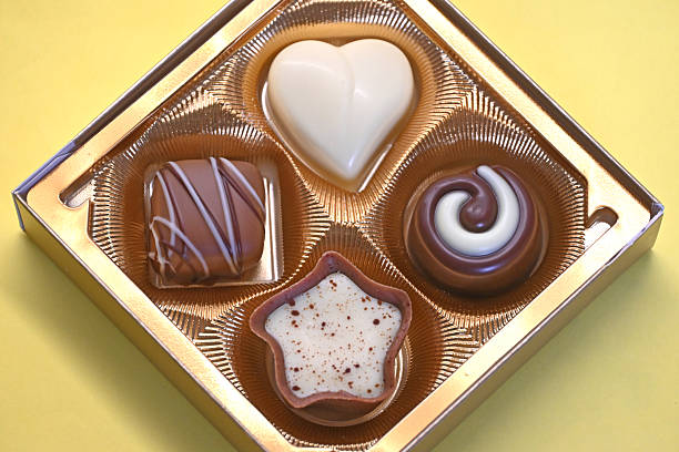 4 different shaped sweet chocolate candies in a square gift box. Chocolate pralines.