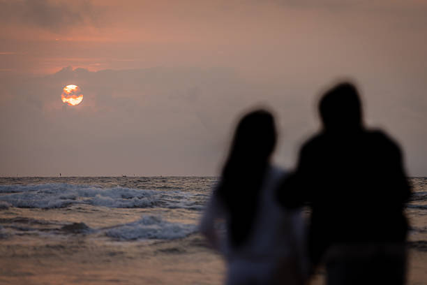 Romantic couple is looking at South China Sea view on the beach at sunrise.Da Nang - Vietnam.