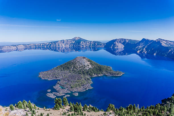 A beautiful blue ocean with a small island in the middle. The island is surrounded by trees and the water is calm
