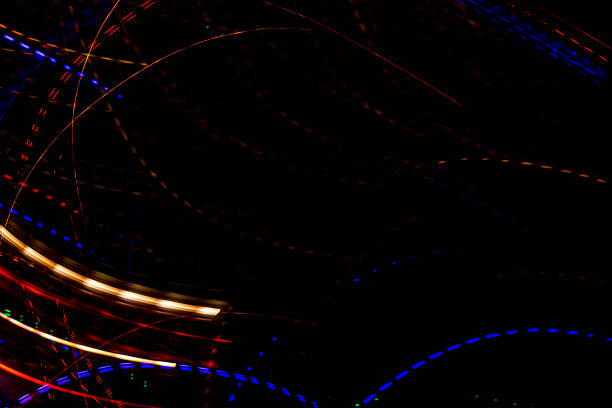 Bright light trails and spots create futuristic patterns against a dark backdrop. Abstract background with glowing curves and spots, made by glowing fiber optic lights.