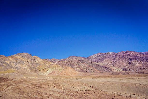 A mountain range with a clear blue sky in the background. The sky is very bright and the mountains are very tall