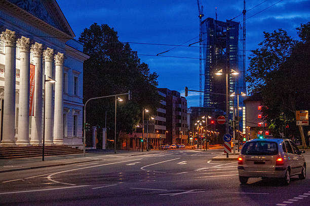 A calm urban street scene during blue hour with streetlights glowing and modern buildings under evening sky