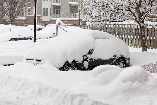 Mounds of a deep winter blizzard storm snow cover a cars in a parking lot.