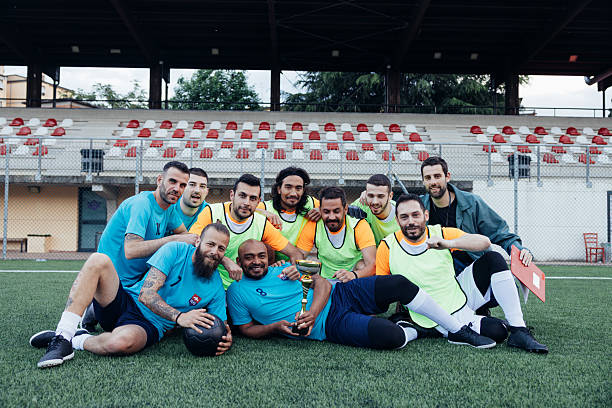 Portraits of adult male amateur soccer players standing on the field. Casual yet proud expressions before or after the match.
