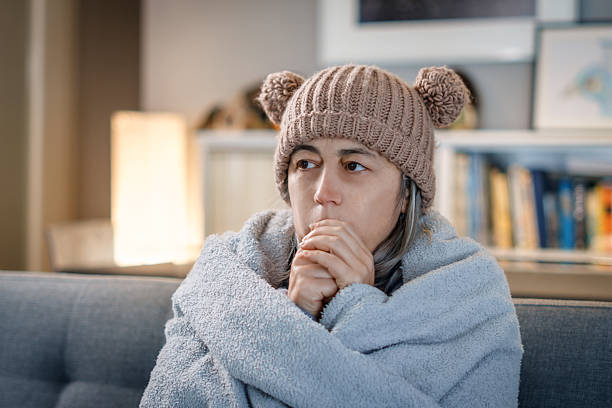 istock Woman feeling cold at home, warming hands wearing winter hat 2263205319
