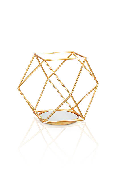 High-end studio photograph of a modern geometric candle holder crafted from gold metal rods with a reflective mirror base. The contemporary wireframe design creates a stylish and elegant home décor piece suitable for candles, tealights, or decorative accents. Shot on a clean white background with a soft reflection, this premium image is perfect for e-commerce listings, interior design catalogs, lifestyle branding, and luxury home accessory promotions.