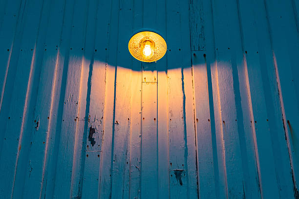Warm light from an outdoor lamp shining on weathered blue wooden planks