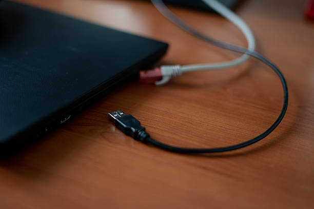 The network cable and USB cable are connected to a black laptop