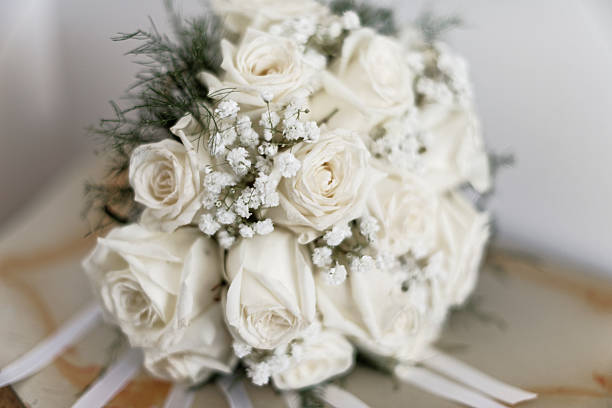 A wedding bouquet of white flowers placed on a table bathed in sunlight by a window