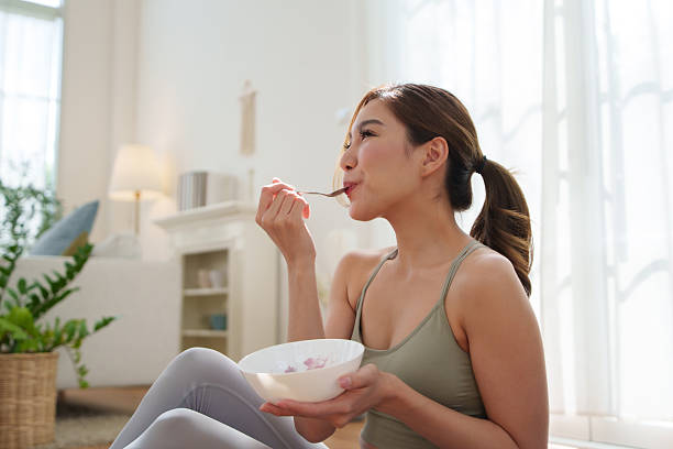 Healthy Asian woman eating yogurt after home workout