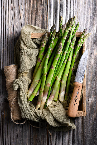 Fresh green asparagus bundle arranged with fabric napkin on wooden background