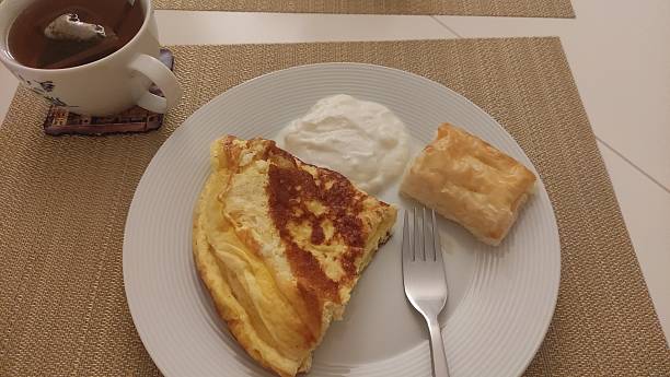 Omelette, yogurt, pastry and tea composing a simple breakfast