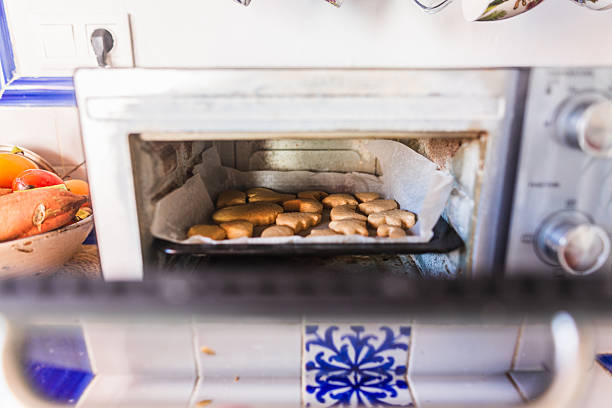 Gingerbread cookies baking on a tray inside a small kitchen oven