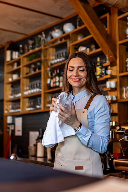 Smiling Female Barista Cleaning Glassware Behind Counter in Cozy Rustic Coffee Shop