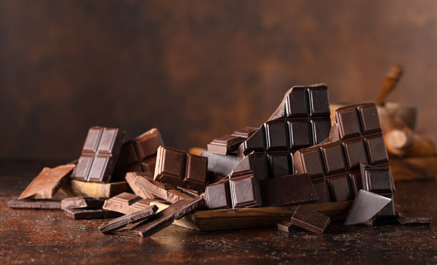 Broken bitter and milk chocolate bars on a brown background.