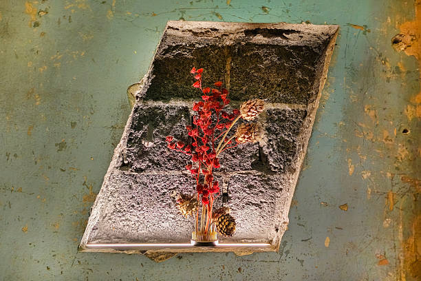 Niche in the wall with a vase and dried flowers. A vase of dried flowers sits on a old brick wall. The flowers are pink and the vase is clear, adding a design element to the interior of the room.