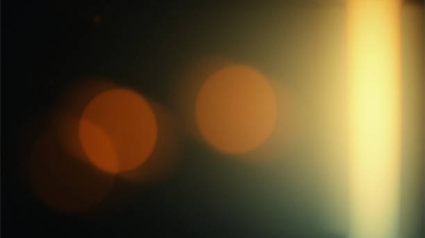 Abstract warm light leak background with dark black shadows, soft orange bokeh circles and a bright vertical yellow-white glow on the right side. Cinematic blurred texture with vintage film look, subtle gradient tones and copy space for creative design, overlays, posters and digital backgrounds.