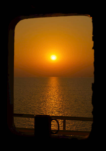 View of the coffee cup and the morning sun near the window of a ship at sea