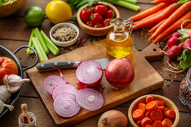 High angle view of freshly sliced and whole organic red onions on cutting board. Cooking or preparing a healthy and nutritine vegetarian meal. Vegan food and ingredients for dieting and wellness