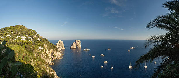 I Faraglioni sea stacks in Capri viewed from Via Krupp, Mediterranean coastline with yachts at sunset, Campania, Italy