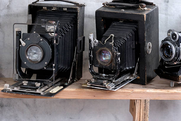 Two classic cameras rest on a wooden shelf, showcasing their unique designs and history.