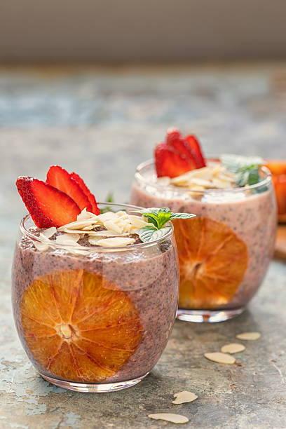 Two glasses of chia seed pudding with fresh strawberries, bloody oranges, almond flakes and mint topping for the breakfast