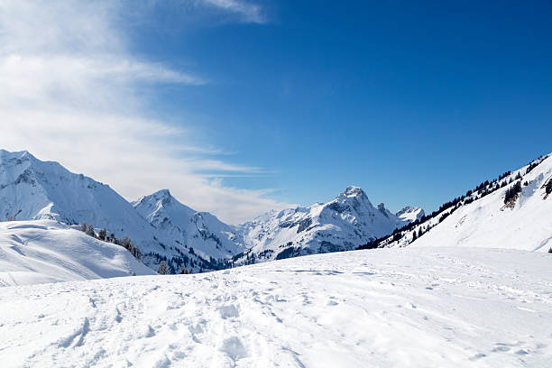 A beautiful winter landscape with snow-covered mountains, clear blue sky on a sunny day.
