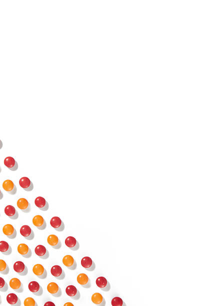 Diagonal Pattern of Orange and Red Candy Balls on White Background