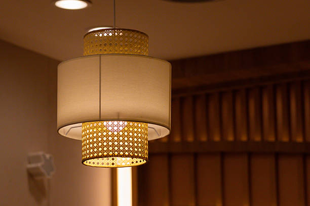 A lamp with a yellow shade is hanging from the ceiling