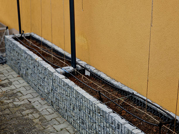 gabion-style raised planter equipped with an integrated irrigation system and vertical supports.